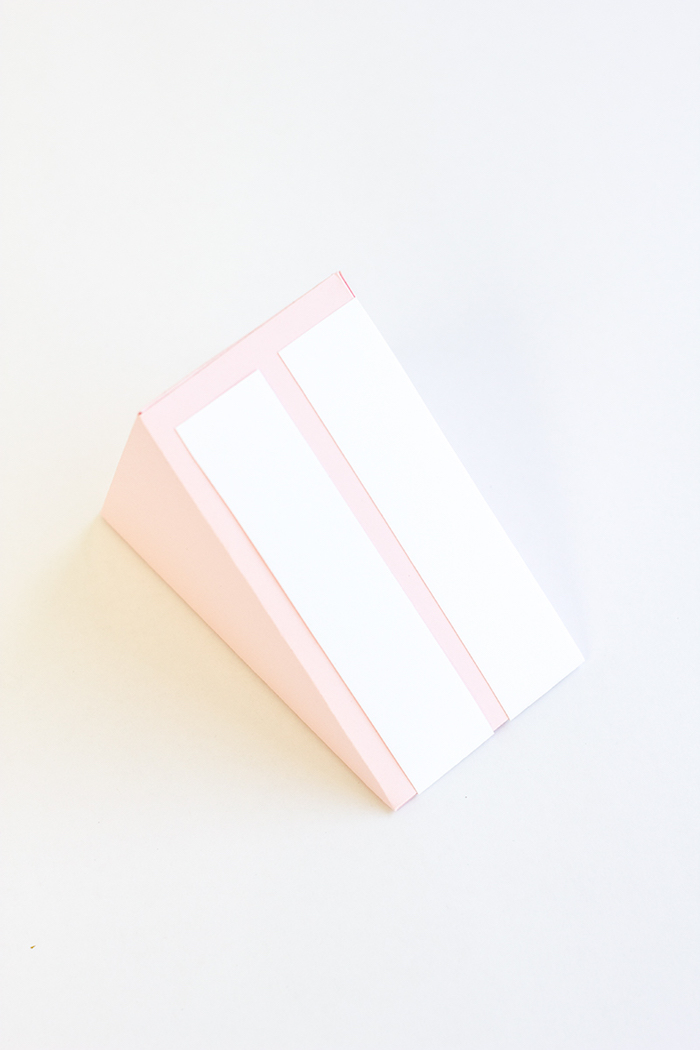 Schachteln falten - ein Stück Torte aus Papier, die weiße Streifen auf rosa Hintergrund