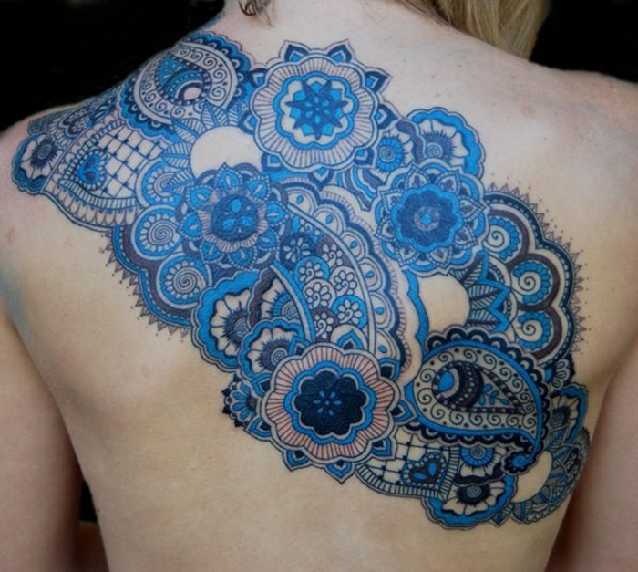 Frau mit Schulter- und Rückentattoo mit kleinen Mandalas in vielen Nuancen von Blau, kleine Ornamente in dunkler Farbe