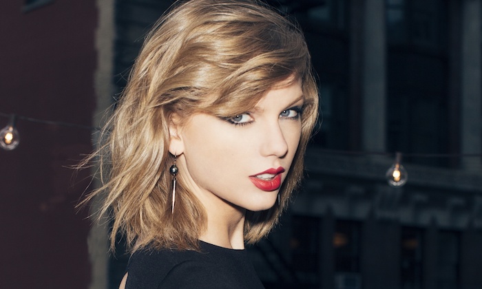 dunkelblonde Haare Taylor Swift mit einem roten Lippenstift und längliche Ohrringe