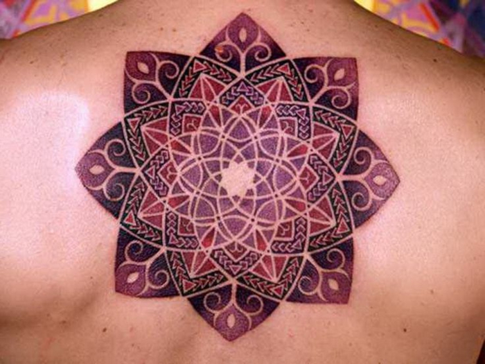 Rückentattoo im Zentrum des Rückens in Weinrot, Lila und Violett, Mandala ohne Konturen mit vielen Triangeln, Rücken mit vielen Muttermalen