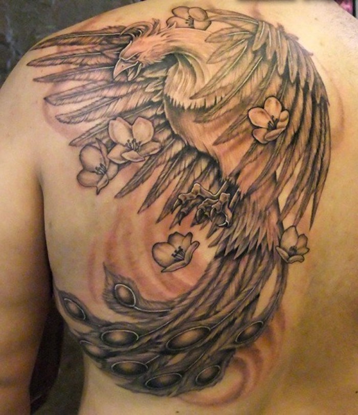 schulterblatt tattoo - ein mann mit einem schwarzen tattoo mit einem großen schwarzen fliegenden phönix mit zwei flügeln mit schwarzen und weißen federn - phönix tattoo mit weißen blumen