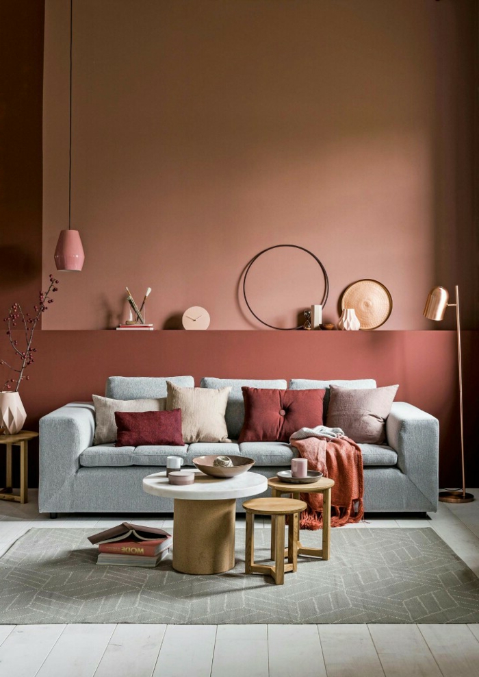 Wohnzimmer Einrichtung, Wandfarbe Apricot, graues Sofa, kleiner Tisch und Hocker, viele Dekoartikel 