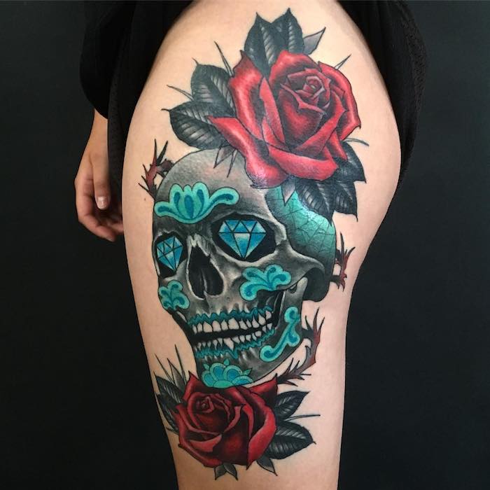 ei n totenkopf mit rosen tattoo - totenkopf mit zwei blauen diamanten und zwei großen roten rosen mit grünen blättern