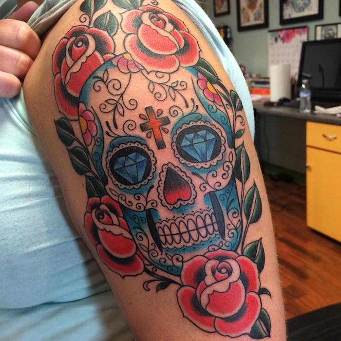 mexikanischer totenkopf tattoo mit blauen diamanten und weißen zähnen und einem orangen kreuz und violetten blumen - totenkopf mit rosen tattoo, totenkopf blumen tattooo