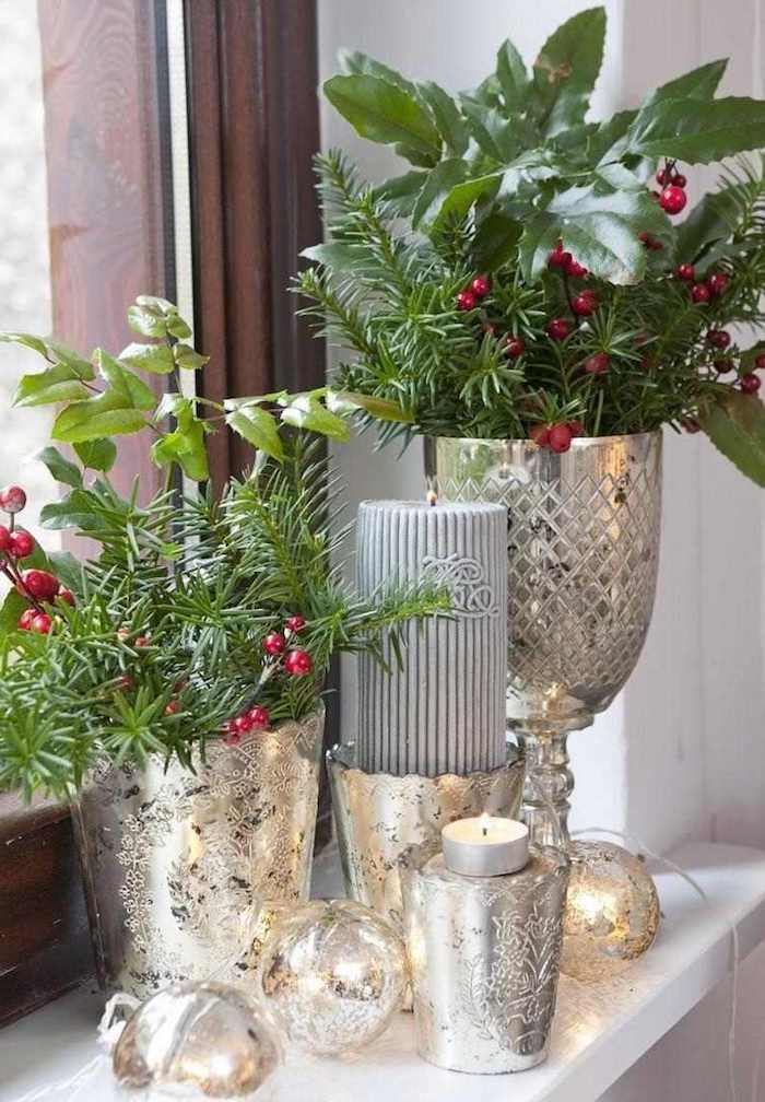 fensterdeko weihnachten basteln glänzende deko ideen silberne vasen kerzen grüne zweige rote früchte