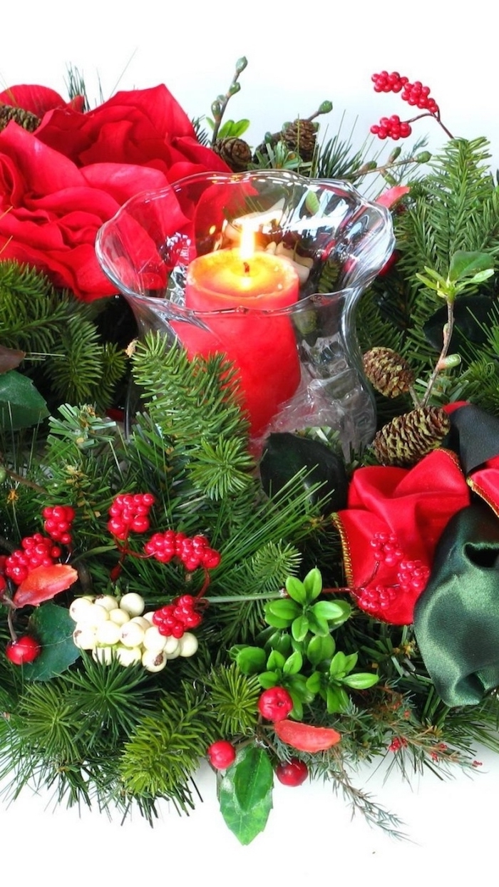 eine Kerze in der Mitte von roten Blumen und grüne Zweige - Weihnachtgesteck