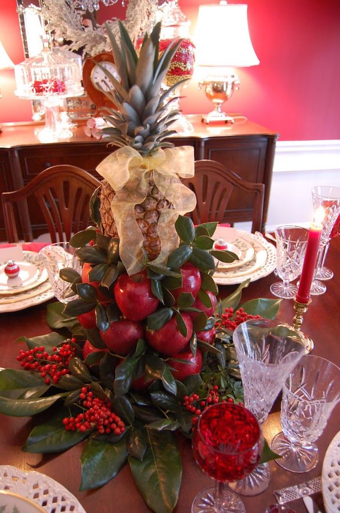Weihnachtsgesteck aus Früchten - Äpfel und Ananas von grünen Zweigen umgeben