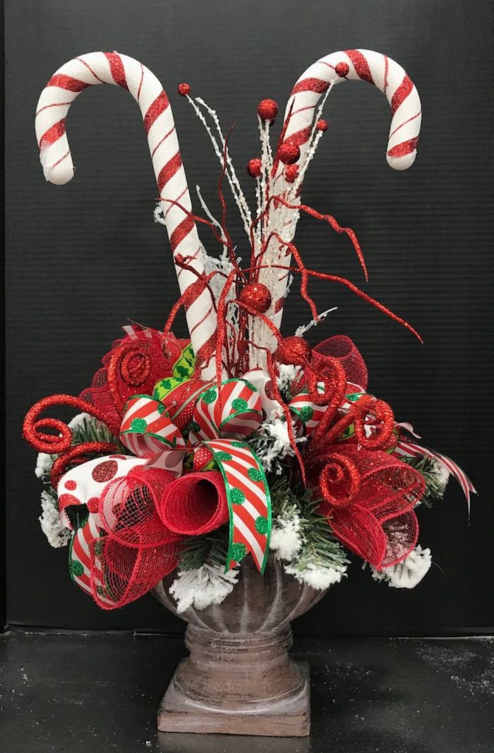 Weihnachtsgesteck aus roten Blumen, Schleifen und Süßigkeiten in einer alten Vase 