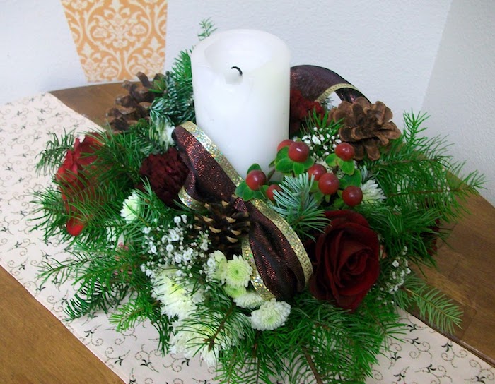 Adventsgestecke aus Naturmaterialien - grüne Zweige und rote Schleife, weiße Kerze