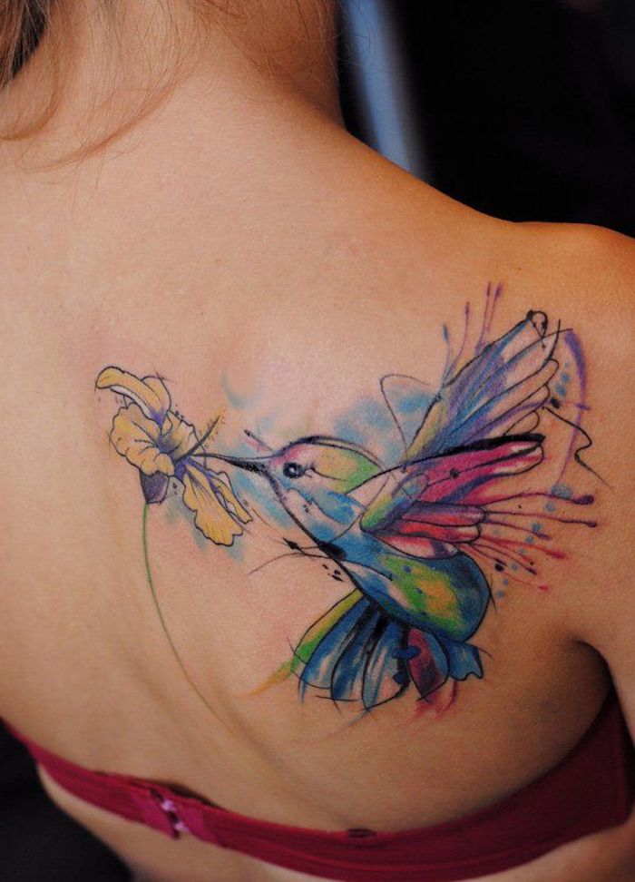 frau mit farbigem kolibri tattoo am rücken, vogel mit blume