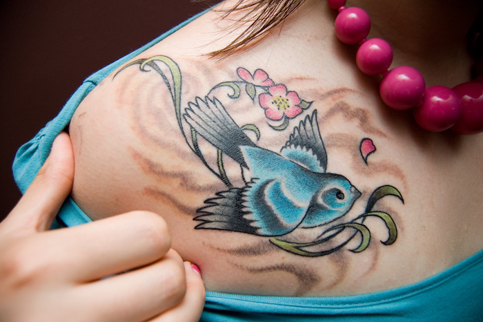 tattoo schwalbe, blauer vogel auf zweig, rosa blumen