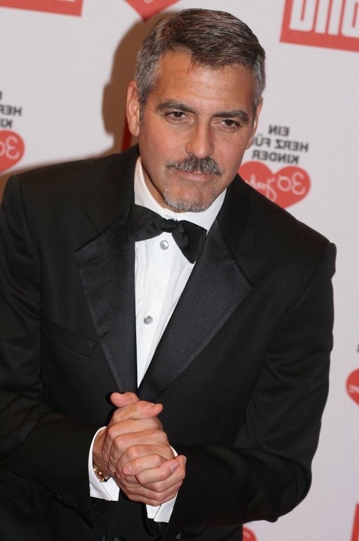 George Clooney schick und elegant wie immer, Kinnbart und Moustache, schwarzer Anzug mit weißem Hemd und Fliege