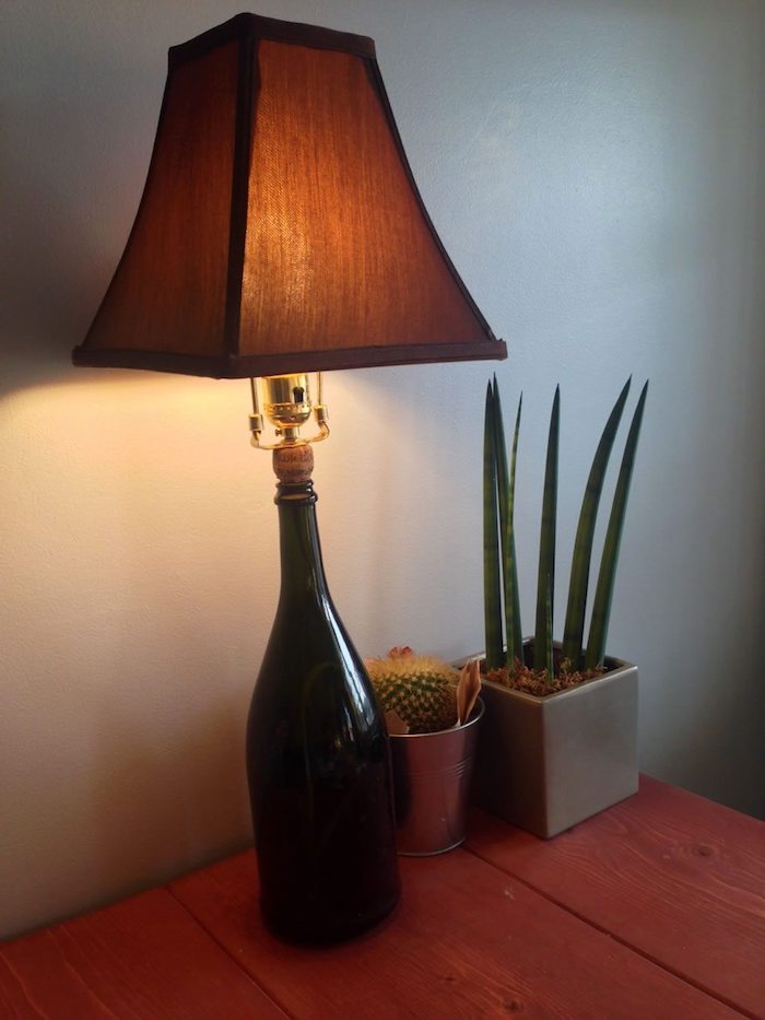 tiasch aus holz - zwei blumentöpfe mit grünen pflanzen - eine lampe aus einer schwarzen großen flasche - flaschenlampe selber bauen