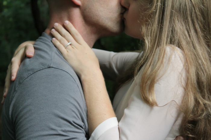 Verliebte Bilder - beide Verliebte küssen sich, nachdem Sie einen Verlobungsring bekommen hat