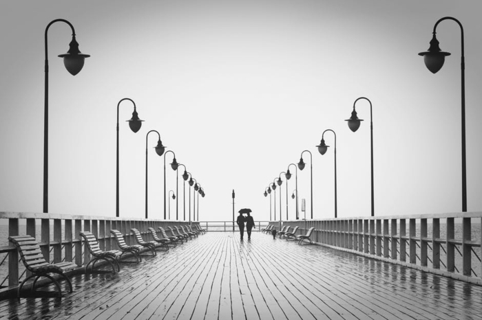 schwarz-weißes Foto von zwei Verliebte, Grüße zum Valentinstag, über eine Brücke gehen