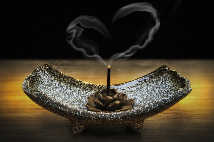 Kerzenständer mit einem Lotos in der Mitte mit einer Duftkerze, deren Rauch ein Herzchen formt - Grüße zum Valentinstag