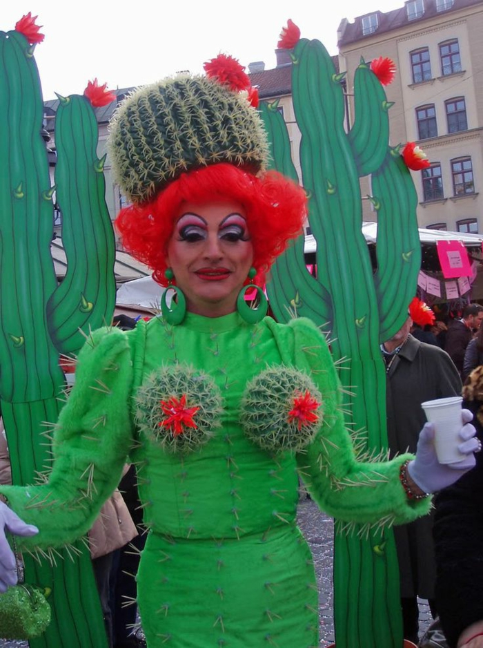 eine Frau verkleidet wie einen Kaktus in einem grünen Kostüm mit einer roten Perüke