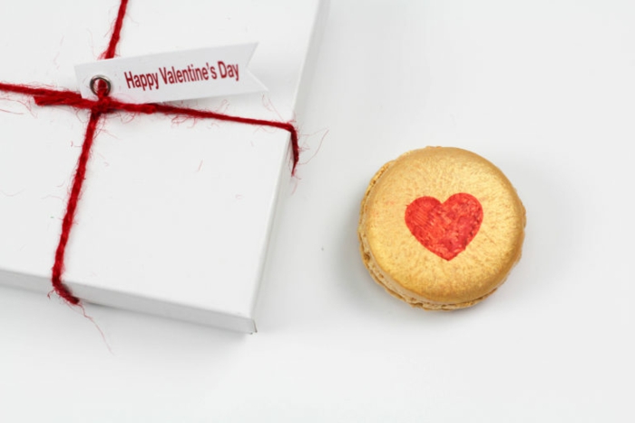Französische Macarons mit roten Herzen zum Valentinstag schenken, mit Geschenkpapier verpackt