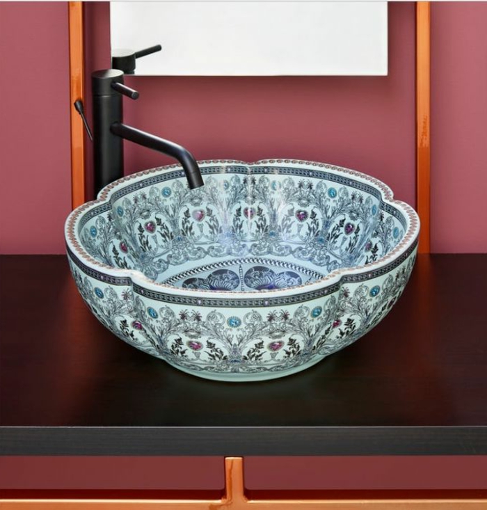 blaue Keramik mit orientalischen Zeichnungen, schwarzer Tisch mit glatter Fläche, schmaler Wandspiegel ohne Rahmen an der aschenpinken Wand