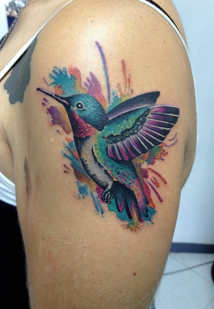 farbiges kolibri tattoo am oberarm, frau mit tätowierung mit vogel-motiv