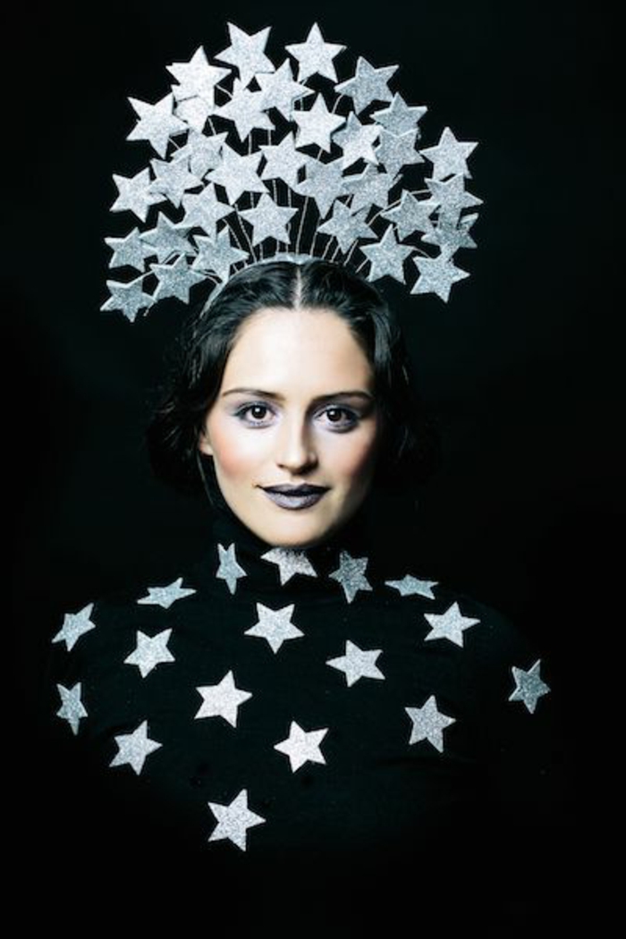 schwarzes Kleid mit silbernen Sternen und eine Krone aus silbernen Sternen-Schablonen, schwarze Haare und Smokey Eye Schminke