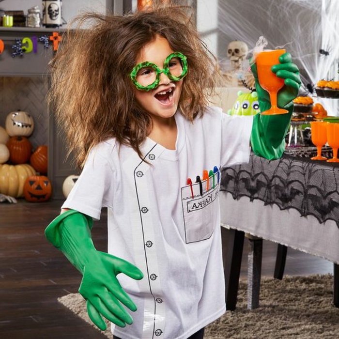 kleines Genie Wunderkind Mädchen verrückte Laborantin mit weißem Hemd und grünen Gummi-Handschuhen mit runden Brillen und einem orangenen Glas mit Gift