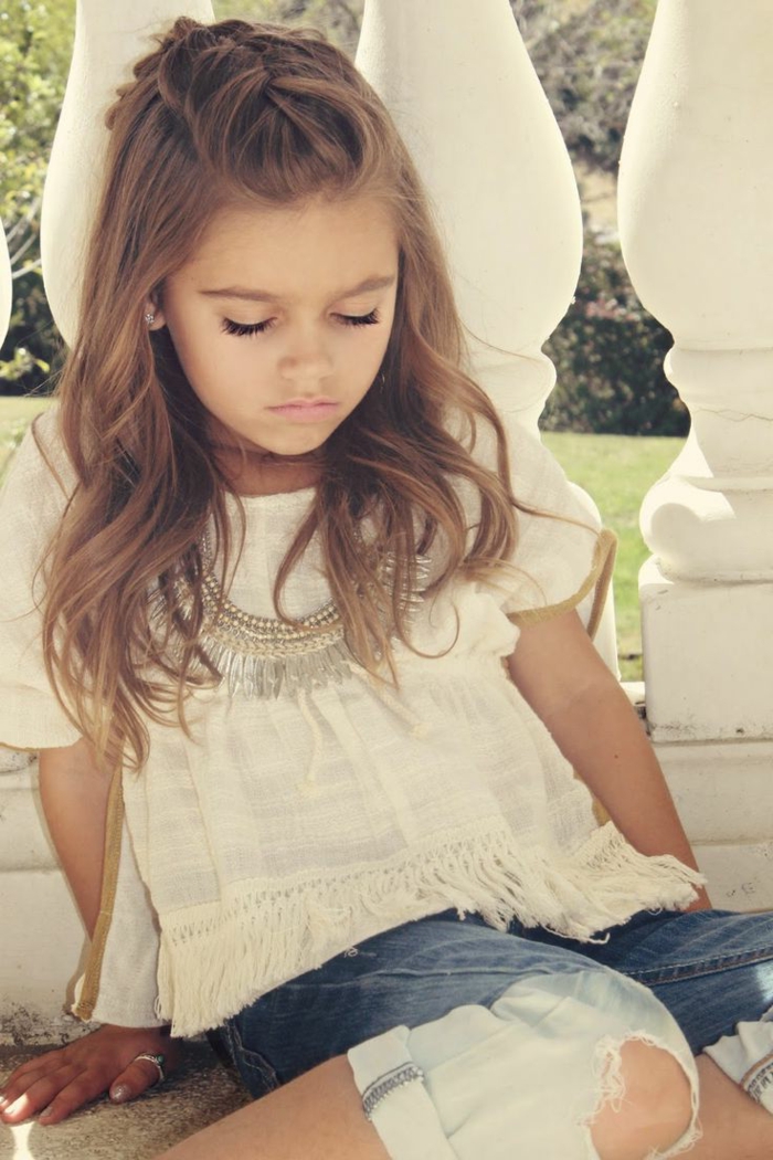 Frisuren Mädchen - eine weiße Bluse und moderne Jeans von einem kleinen Mädchen