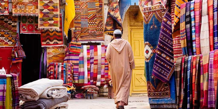 ein Mann mit hellen Kleidern auf dem Agadir Markt für orientalische Stoffe, Teppiche und Gardinen