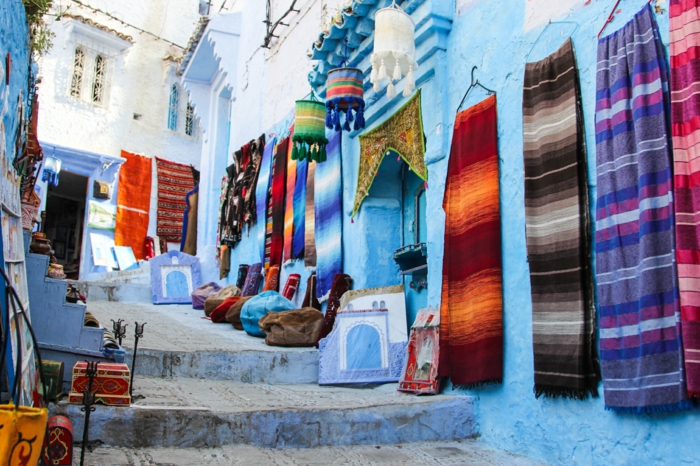 die Blaue Stadt in Marokko, Straße mit Treppen - marokkanischer Markt für Dekorationen und Stoffe, Schals und Kissenbezüge, kleine dekorative Kisten aus Holz und orientalische Wandbilder