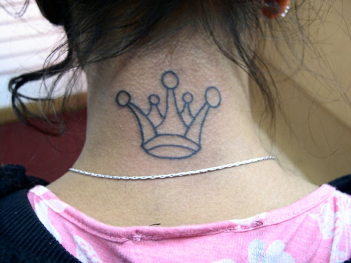 eine Krone mit geometrischen Figuren - Tattoo Nacken und eine silberne Kette