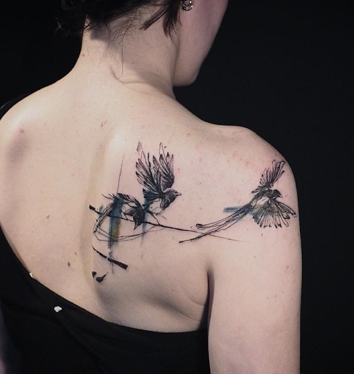 tattoo freiheit, frau mit schwarz-grauer tätowierung mit vogel-motiv am rücken