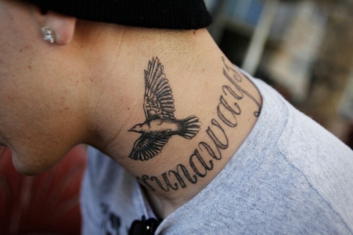 tattoo freiheit, mann mit tätowierung am hals, schriftzug in kombination mit fliegendem vogel