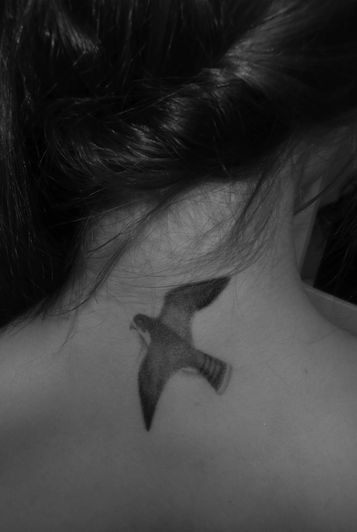 eine Schwalbe als Tattoo im Nacken mit herausgesteckten Flügeln