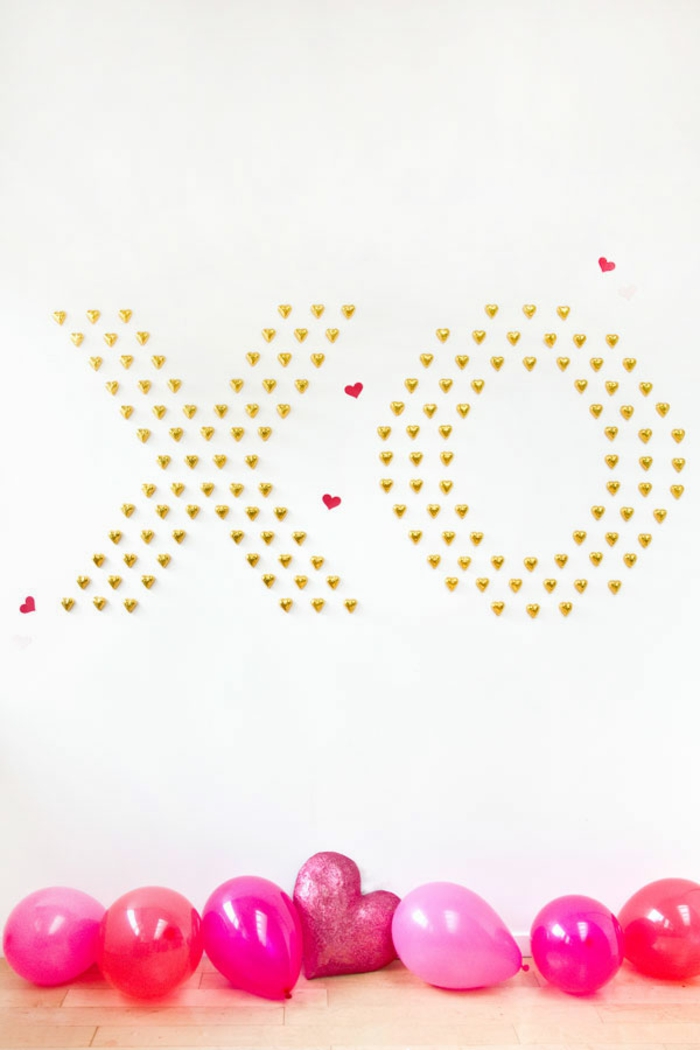 Aufschrift aus Schokoladen Herzen an der Wand, rote und rosafarbene Luftballons auf dem Boden, romantische Überraschung zum Valentinstag