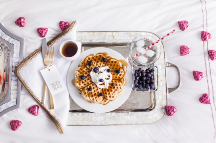 Frühstück im Bett zum Valentinstag, belgische Waffeln mit Sahne und Blaubeeren, heißer Kaffee und Wasser mit Eis