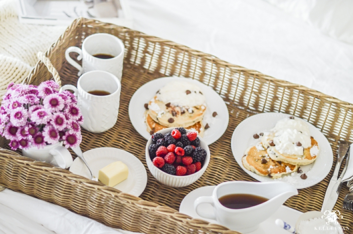 Frühstück im Bett zum Valentinstag, Pfannkuchen mit Eis und Beeren, heißer Kaffee und kleiner Blumenstrauß