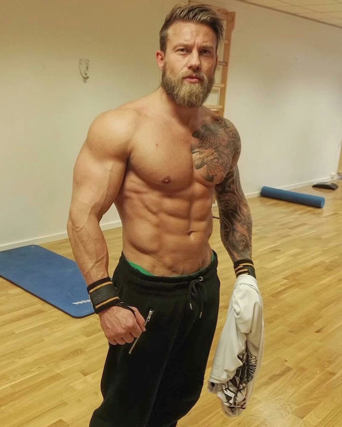 vollbart in blonder farbe fitnessmodel mann cooler männlicher look trendy im saal sein muskeln tattoos bart