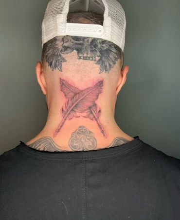 zwei gekreuzte federn tattoo mann
