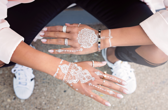 weißes henna, große silberne ringe mit steinchen, temporäre tätowierungen mit weißem henna an den händen