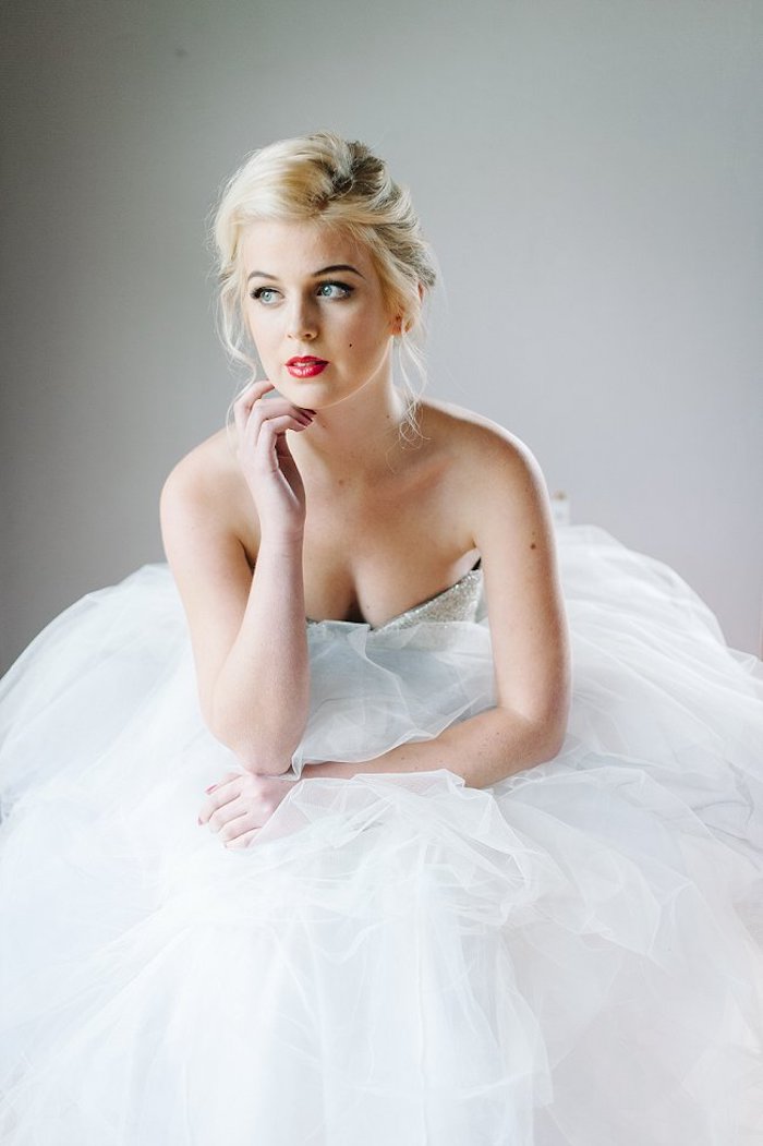 Marilyn Monroe Inspiration für Bräute, trägerloses Brautkleid mit Glitzer-Oberteil und Tüllrock, elegante Hochsteckfrisur, schwarze Mascara und knallroter Lippenstift