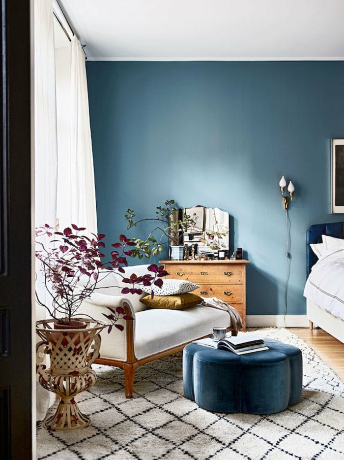 eine Leseecke im Schlafzimmer modern gestalten, weißer, bequmer Sessel, ein blauer Hocker