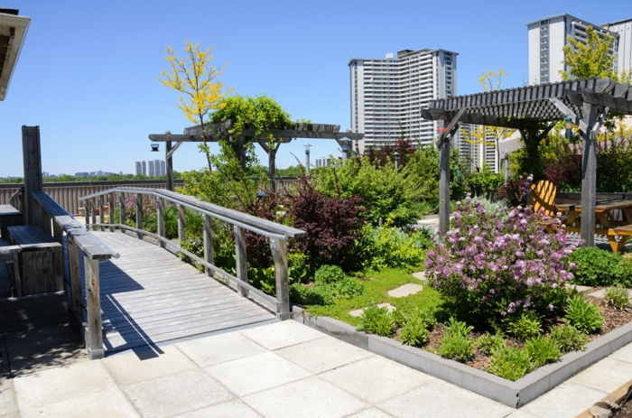 zwei Pergolen, eine Brücke, lila Blumen, eine originelle Terrassenbepflanzung