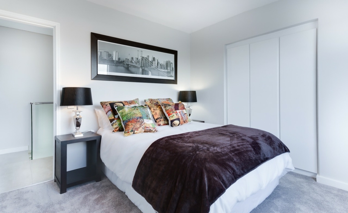 eingebauter weißer Schrank, ein großes Doppelbett mit bemusterten Kissen, Schlafzimmer modern einrichten
