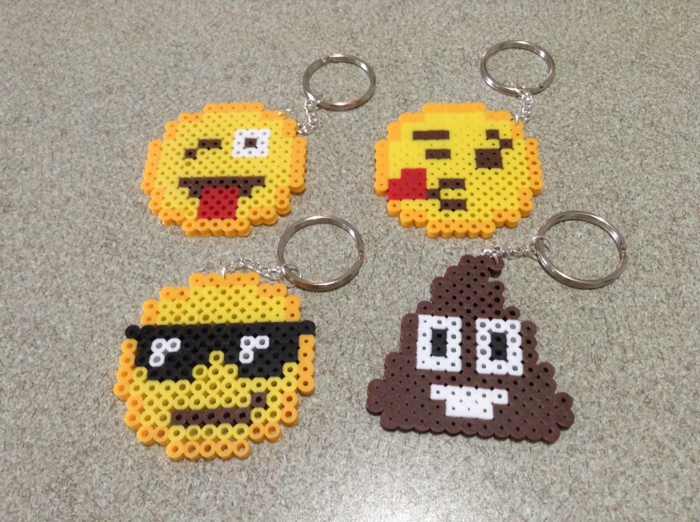 vier Schlüsselanhänger mit Emoji Gesichter aus Steckperlen, jedes hat eine verschiedene Miene