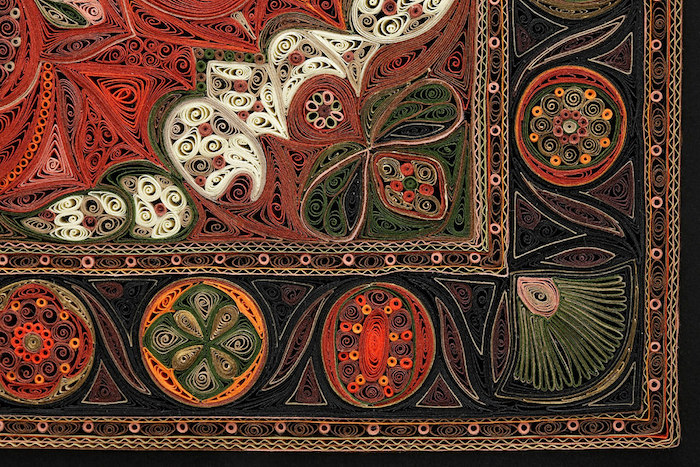 ein quilling bild mit einem teppich, bastelideen für erwachsene, ei n teppich aus grünen, roten, schwarzen, weißen, braunen und orangen papierstreifen