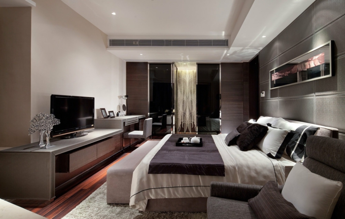 modern Schlafzimmer dekorieren, ein großes Doppelbett, ein grauer Sessel, ein Fernseher