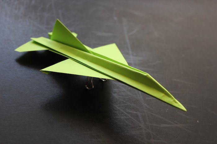 ein tisch und ein kleiner grüner papierflieger, basteln mit papier, ein grüner jagdflugzeig aus papier