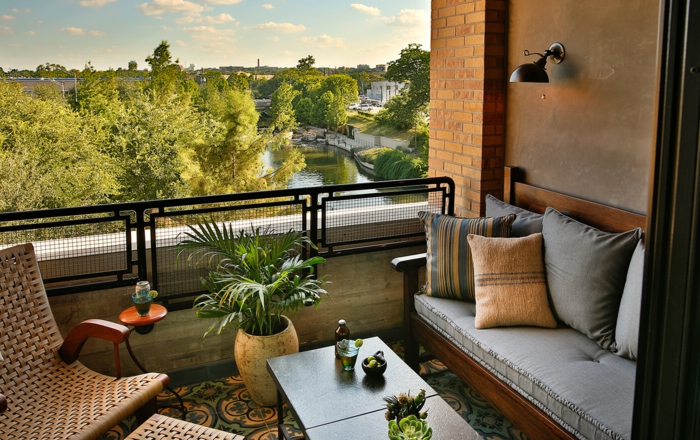 Rattan Liegestuhl, ein Sofa mit vielen Kissen, ein Blumentopf, Terrasse dekorieren