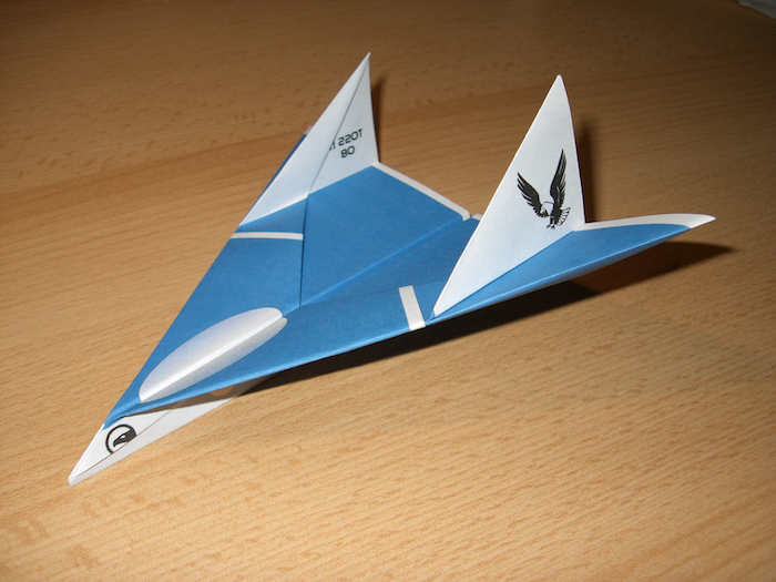 ein kleiner blauer papierflieger mit einem kleinen schwarzer fliegenden adler, bester papierflieger der welt