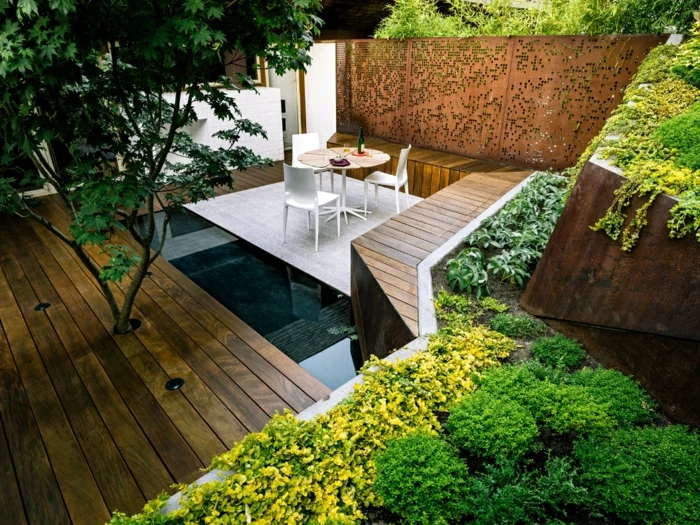 Terrasse mit einem Wasserspiel, Gartenmöbel wie auf eine Insel, ausgefallener Sichtschutz